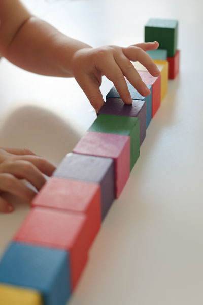 Child Hands Playing with Montessori Toys Education - Family Life Tips Magazine